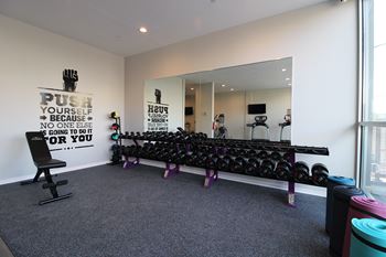 A gym room with a mirror, weights, and a motivational quote on the wall.